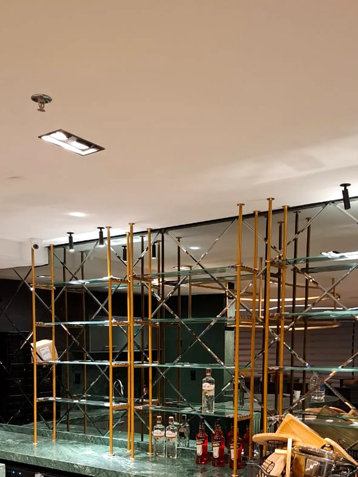 Estrutura metálica dourada com prateleiras de vidro instalada sobre balcão