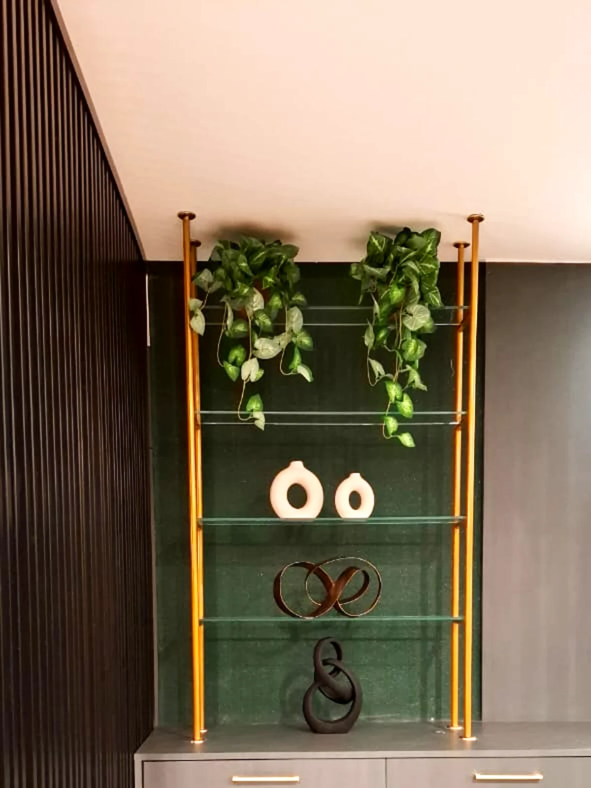 Estante decorativa com estrutura metálica dourada e prateleiras de vidro